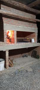 un horno de ladrillo con un fuego dentro de él en Aquellos Diaz- Cabaña con vista a las Sierras - Pileta - Wifi - Cochera techada - Aceptamos mascotas en Huerta Grande