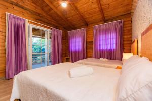 2 camas en una habitación con cortinas moradas y ventana en Villa Panorama, en La Lomota