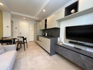 uma sala de estar com uma televisão grande e uma cozinha em Vilu Suite Centro em Polignano a Mare