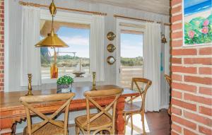 uma sala de jantar com uma mesa e cadeiras e uma janela em Nice Home In Hvide Sande With 3 Bedrooms, Sauna And Wifi em Nørre Lyngvig