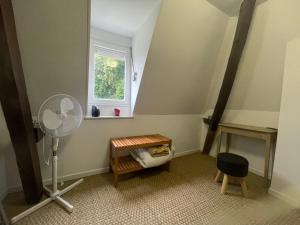 a room with a fan and a table and a window at Chambre privée cosy in Noyon
