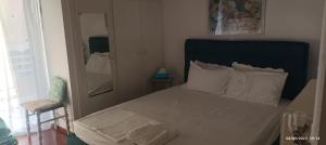 a bedroom with a bed with a blue headboard and a mirror at City Break Nearby Metro And Bus Express Airport in Athens