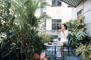 una mujer sentada en una mesa en un jardín en Chapter 127 en Tainan
