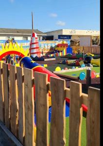 a wooden fence in front of a playground at Julie’s retreat in Abergele