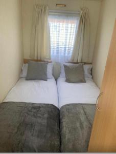 two beds in a small room with a window at Julie’s retreat in Abergele