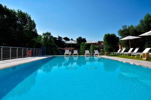 une grande piscine bleue avec des chaises et des parasols dans l'établissement Four Points by Sheraton Siena, à Sienne