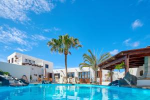 a large swimming pool with palm trees and buildings at Casa Rural Nel in Tinajo