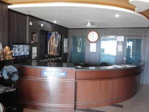 a reception desk with a clock on the wall at Hotel Shoven in Dāvangere
