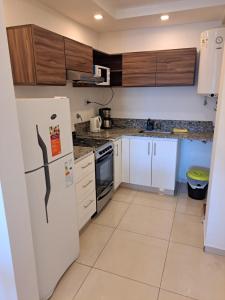 cocina con nevera blanca y armarios de madera en Departamentos 1943 en Villa Constitución