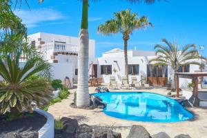 a villa with a swimming pool and palm trees at Casa Rural Nel in Tinajo