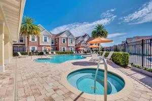 a swimming pool with an umbrella and some houses at Magical Residence Resort, 5 min Disney in Orlando