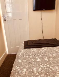 a bedroom with a bed and a door with a television at AC Lounge 36 (Room D) in Rochford