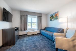 a living room with a blue couch and a tv at Independence Stay Hotel and Long term suites in Houghton
