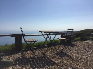 a picnic table and two chairs sitting next to the water at Harbour View Capel Le Ferne in Folkestone