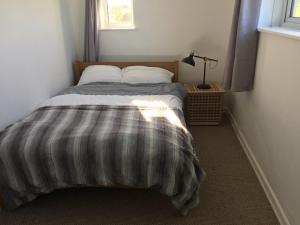 a bedroom with a bed with a striped blanket at Harbour View Capel Le Ferne in Folkestone