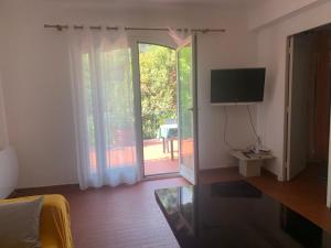 a living room with a tv and a sliding glass door at Maison calme ensoleillée in Nice