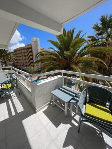 a balcony with a table and chairs and palm trees at Apart Hotel Ponderosa in Playa de las Americas