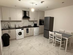Lovely Hillingdon Family Holiday Home - 7 bedrooms في Ickenham: مطبخ به أجهزة بيضاء وطاولة وكراسي