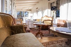 ein Wohnzimmer mit Stühlen, Tischen und Fenstern in der Unterkunft Paradiesische Villa mit Seeblick, großem Wintergarten und Außenterrasse mit Grill in Ulricehamn
