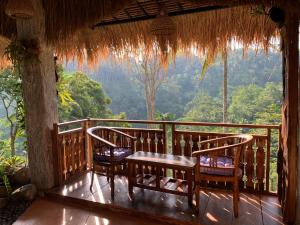 a porch with a table and chairs on a balcony at Bali Inang Jungle View in Tampaksiring