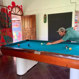 un uomo che gioca a biliardo in una stanza con tavolo da biliardo di Stella Hostel Copán a Rovine di Copán