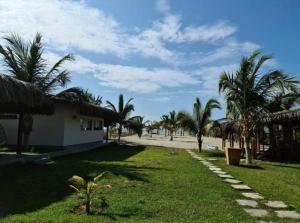 un camino que conduce a una playa con palmeras y un edificio en Aquamare Bungalows en Cruz de Pizarro