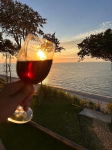 een persoon met een glas wijn voor de oceaan bij Rewal Hevenia The Best View ever in Rewal