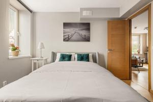 - une chambre avec un grand lit blanc et une porte en bois dans l'établissement Dinbnb Apartments I Roof Terrace & Laundry in Sandviken, à Bergen