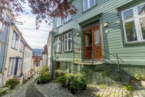 a green house with a door on a street at Dinbnb Homes I Cozy Cellar Apartment in Historical Cobblestone Street" in Bergen