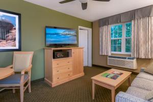 sala de estar con TV de pantalla plana y mesa en Acadia Inn en Bar Harbor