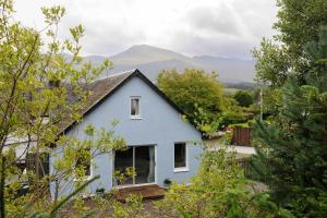 a blue house with mountains in the background at Stunning House near Fort William - Taigh Sona in Spean Bridge