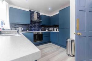 a blue kitchen with a white counter and blue cabinets at Stunning House near Fort William - Taigh Sona in Spean Bridge