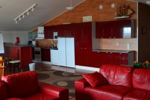 a living room with red furniture and a kitchen at Hotel Reima Country Center in Jämijärvi