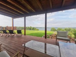 a deck with chairs and a glass table and a view at Mazurski Horyzont in Leleszki