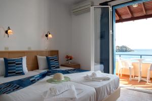 a bedroom with two beds with a view of the ocean at Hotel Kyma in Skala Eresou