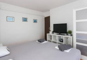 Dieses weiße Zimmer verfügt über 2 Betten und einen TV. in der Unterkunft Light blue, sea view terrace in Dubrovnik