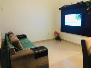a living room with a couch and a flat screen tv at Casa Spar do Atlântico com Piscina in Maricá