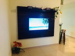 a television on a wall in a living room at Casa Spar do Atlântico com Piscina in Maricá