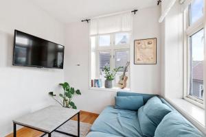a living room with a blue couch and a tv at Dinbnb Apartments I Cozy 1-Bedroom Nestled in the Heart of Bergen in Bergen