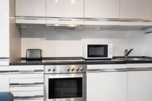 a kitchen with a stove and a microwave at Dinbnb Apartments I Cozy 1-Bedroom Nestled in the Heart of Bergen in Bergen