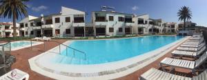 a large swimming pool with lounge chairs in front of a building at Los Balandros 216 in Maspalomas
