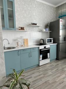 cocina con armarios azules y nevera en ExpoNewLife2 en Astaná