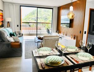 una sala de estar con una mesa con platos y copas de vino en Apartamento Alto Padrão Ubatuba en Ubatuba