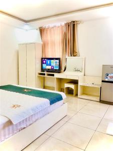 a bedroom with a bed and a desk with a television at Holiday Hotel in An Khê