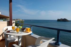 a table on a balcony with a view of the ocean at Hotel Kyma in Skala Eresou