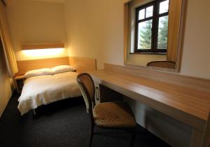 Habitación con escritorio, cama y espejo. en Absolwent en Zieleniec