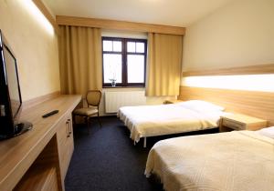 ジェレニエツにあるAbsolwentのベッド2台とテレビが備わるホテルルームです。
