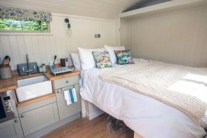 a small bedroom with a bed and a sink at Shepherds Huts Tansy & Ethel in rural Sussex in Arundel