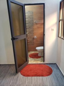 a bathroom with a toilet and a red rug at Fafape in Lomé
