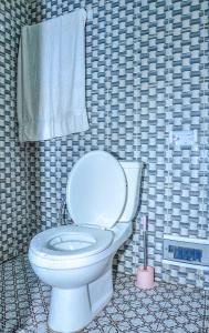 a bathroom with a white toilet in a tiled wall at LES LOGIS DE NOUVELLE ROUTE BASTOS in Yaoundé